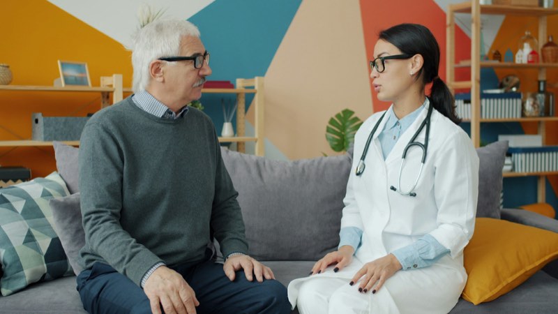 Doctor talking with an older man on a couch